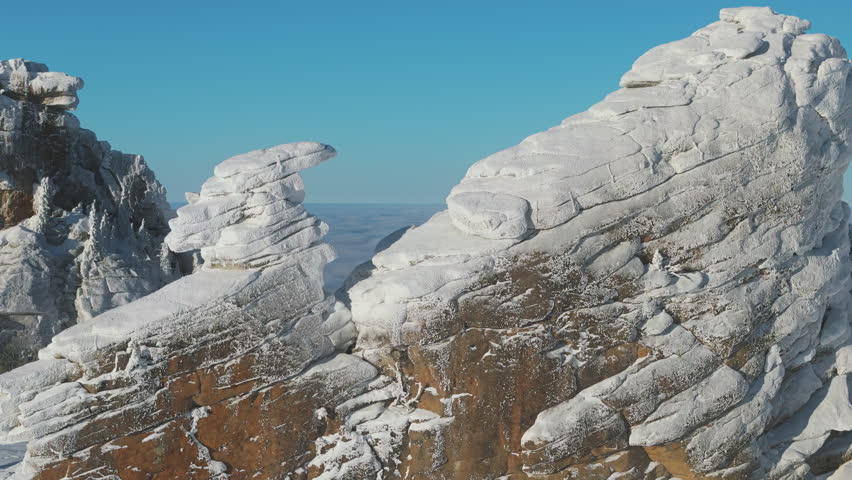 A close pass reveals a ship like tor on the Sheregesh ridge under a clear sky. Fine rime clings to rock and conifer while the camera eases toward the cloud edge over silent Siberia