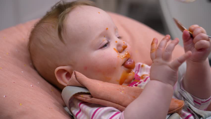 Joyful infant explores first foods, creating delightful and messy mealtime of discovery