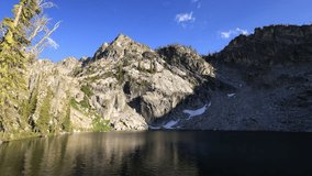 Lower Trail Creek Lake in Sawtooth National Forest in Idaho at dusk, where drifting summer clouds reflect off calm waters beneath rugged mountain peaks. - Powered by Shutterstock - Get 15% off with code: PIKWIZARD15