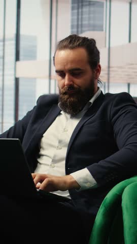 Vertical Video CEO practices mindfulness in his modern office listening to meditation music through a mobile app. Calm posture and closed eyes reflect a moment of peace amid corporate pressures