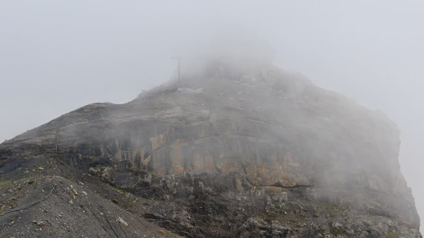In Engelberg, wispy clouds drift like smoke through the alpine air, curling around mountain peaks and blanketing the valley in soft fog. Switzerland, August 15, 2025
