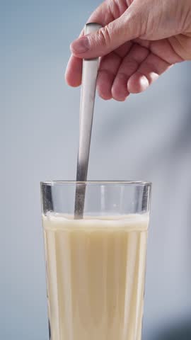 human hand mixing protein powder with water in glass.  whey sports nutrition. dry mixture for preparation of sporting or dietary drink.