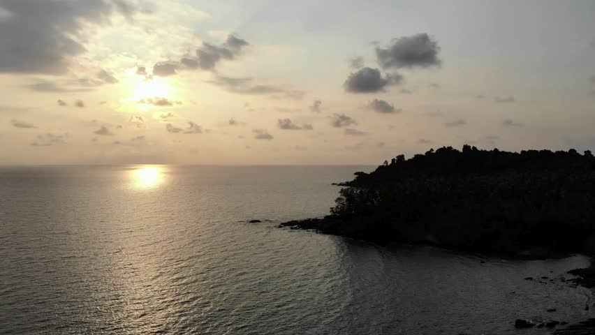 The sun sets over a tranquil ocean, casting a golden glow on the water