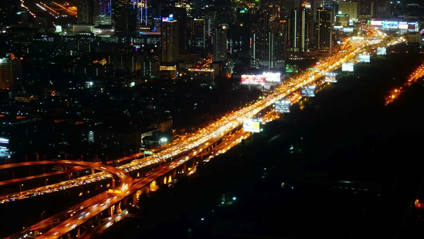 Aerial view of city highway at night with bright lights and modern buildings