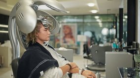A woman sits under a climazone device in a hairdresser's salon. The latest technologies and hairdresser's assistants. - Powered by Shutterstock - Get 15% off with code: PIKWIZARD15
