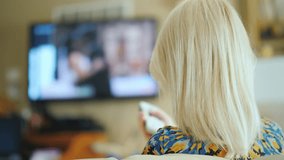 A Woman Is Watching Tv In The Living Room Rear View Holds A Remote Control 4k - Powered by Shutterstock - Get 15% off with code: PIKWIZARD15