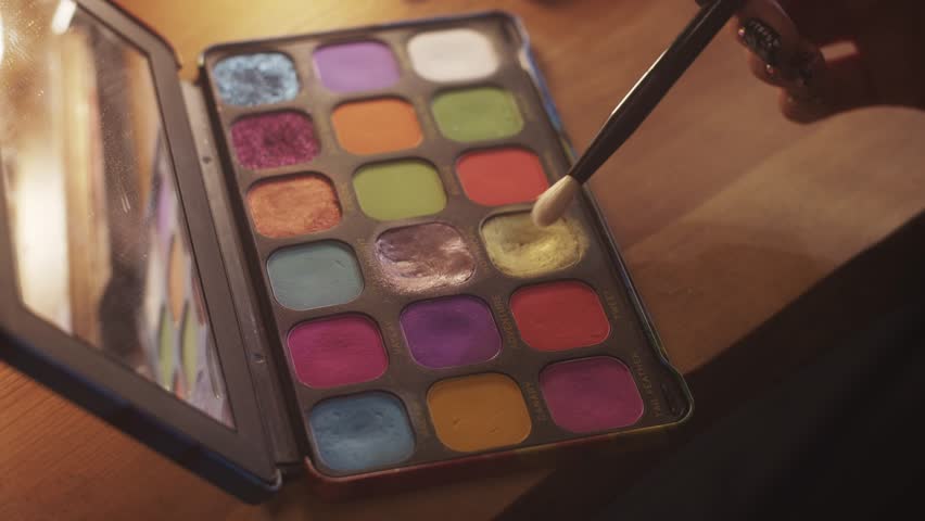 Makeup artist picking eyeshadow with brush from palette