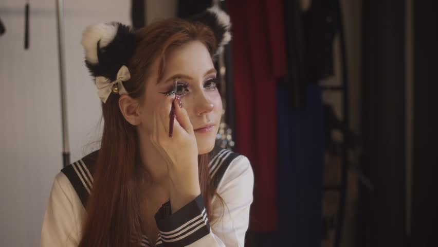 Young woman in cosplay costume applying eye makeup
