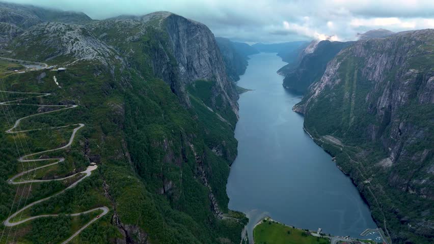 Experience the breathtaking beauty of Lysebotn fjord in Norway, where dramatic cliffs meet serene waters. Witness the intricate roads that weave through lush greenery and steep mountains.