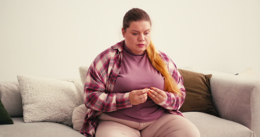 Overweight Plus Size Woman holds pregnancy test anxiously examining result. Female shows extremely happy emotions after seeing positive picture in kitchen