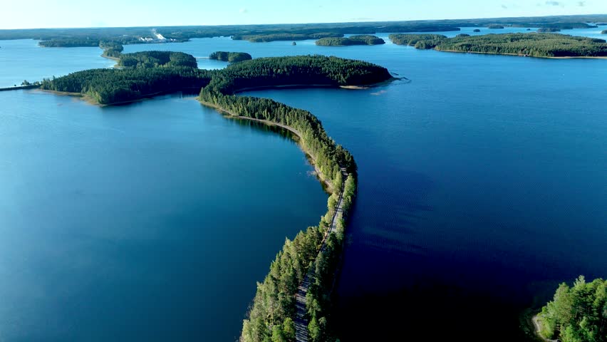 Experience the serene beauty of Punkaharju, Finland, where lush forests and tranquil waters meet. a road between lakes and green forest at Punkaharju Nature Reserve 