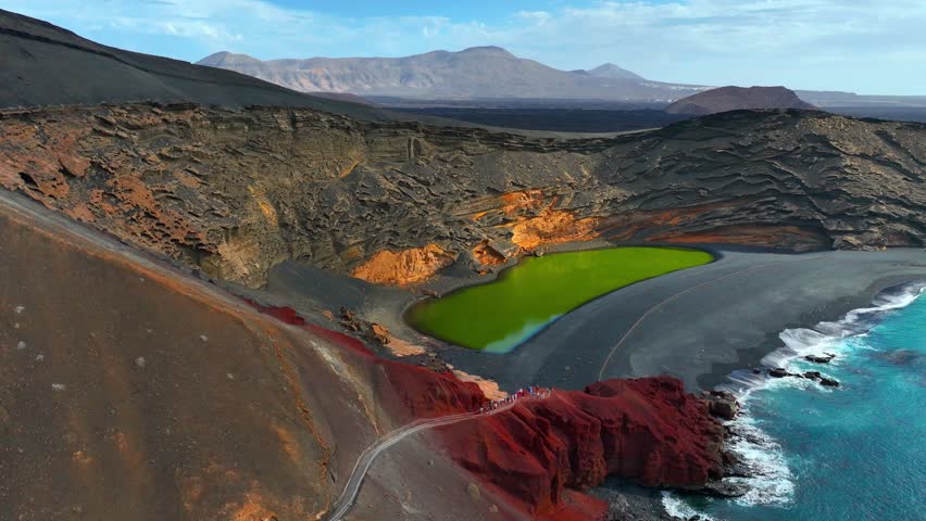 orbiting establishing shot of Lanzerote iconic landscape of volcanic lake el Golfo and black beach, drone shot, aerial view of Lanzerote landscape, Canary islands, Spain. High quality 4k footage