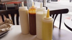 On the table in the diner there are bottles with various sauces such as mustard, mayonnaise, ketchup, hot sauce and curry sauce. High quality 4k footage - Powered by Shutterstock - Get 15% off with code: PIKWIZARD15