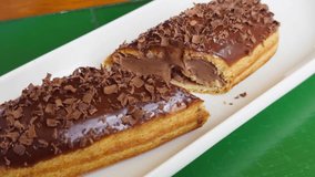 Fresh sweet eclair cake with cream cheese and chocolate chips on the table in a cozy cafe. High quality 4k footage - Powered by Shutterstock - Get 15% off with code: PIKWIZARD15