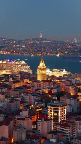 Vertical view of the historic Galata Tower standing out among the illuminated rooftops and modern skyscrapers of Istanbul's skyline at night