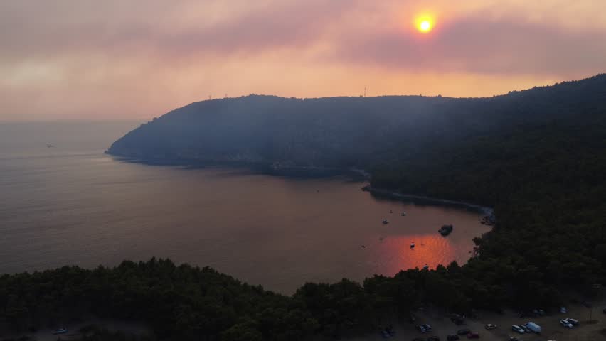 Aerial drone footage of sunset over the Adriatic Sea in Montenegro, with warm orange sunlight reflecting on water. A small airplane appears briefly as the drone flies forward, creating a scenic view.