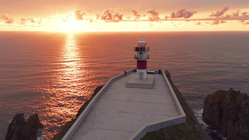 Aerial view of Faro do Cabo Ortegal Lighthouse at sunset in Galicia, Northern Spain. Remote lighthouse on high cliff where Atlantic Ocean meets the Cantabrian Sea. Scenic coastal landscape.
