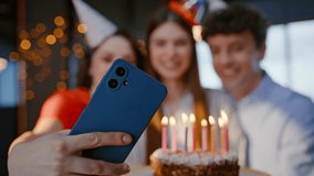 Cheerful businesswoman blowing candles on birthday cake at office party closeup. Happy young team making selfie on smartphone celebrating together. Smiling group colleagues congratulating woman boss - Powered by Shutterstock - Get 15% off with code: PIKWIZARD15