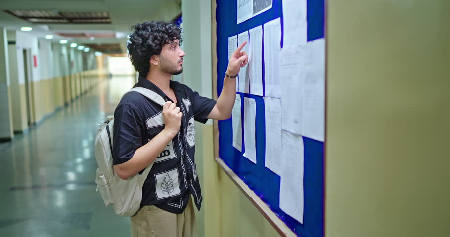 Indian serious young adult gen z student look on board do check results report failed in exam feel bad indoor college place. Male read new notice name list data project schedule deadline inside campus