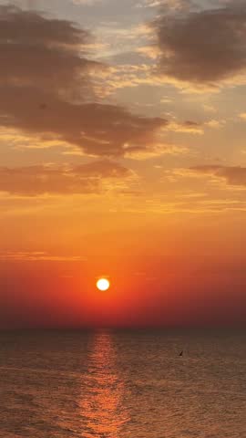 Sunset over ocean with vibrant orange and red hues reflecting on water, romantic atmosphere