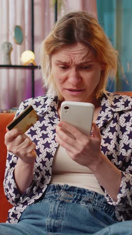 Angry stressed woman trying to pay online shopping with smartphone blocked credit card smartphone. Annoyed Caucasian girl buying bank refuse problem unsuccessful payment lack of money balance at home.