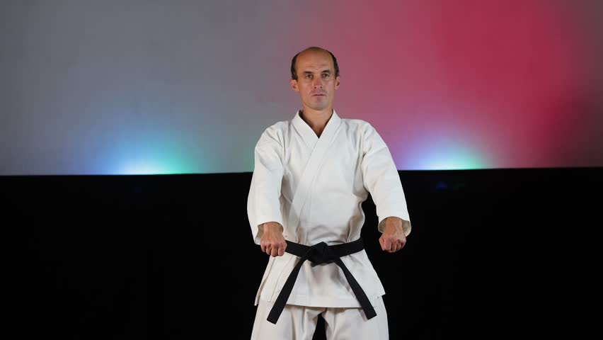 A young athlete practices formal exercises against a colorful background with flashing lights