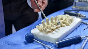 Unrecognized male professional points at the dummy of spine. Educator displays the usage of instrument at the model for students. Close up. - Powered by Shutterstock - Get 15% off with code: PIKWIZARD15