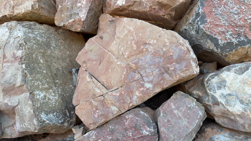 Closeup motion on triangle shaped sand and pink color rough texture rock with large cracks in rock wall 4k