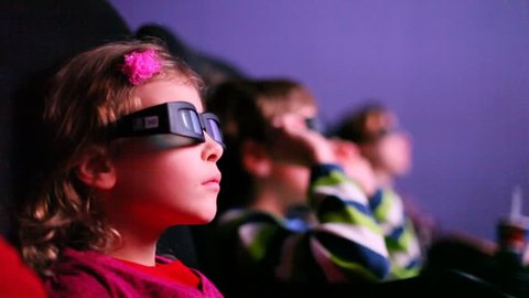 Three kids looking to a 3D movie smiling