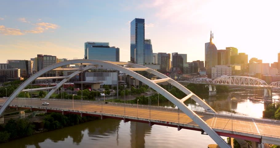 Driving cars on bridge highway near high-rise buildings in downtown district of Nashville, Tennessee, USA. American city with business financial district at sunset.