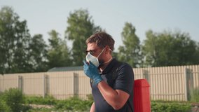 man gardener carrying backpack sprayer wearing mask and sunglasses walking through field with blurred trees background in soft sunlight rural agriculture scene - Powered by Shutterstock - Get 15% off with code: PIKWIZARD15