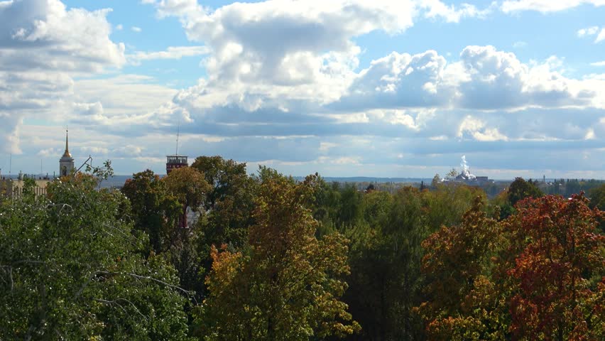 Scenic aerial tilt down over colorful autumn forest under dramatic cloudy sky. Nature landscape with vibrant fall foliage. Perfect for travel, seasons, environment, and cinematic back