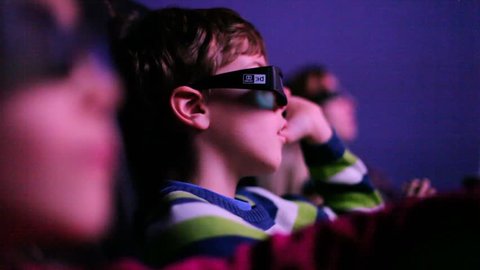Three children in cinema looking to a 3D movie