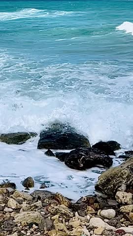 Close-up slow motion of sea waves hitting rocks, blue water shimmering in the sun. Calming and inspiring video for meditation, mindfulness, motivation and social media reels.