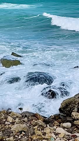 Close-up slow motion of sea waves hitting rocks, blue water shimmering in the sun. <Calming and inspiring video for meditation, mindfulness, motivation and social media reels.