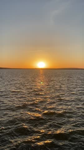 Sunset over the sea shore with waves, golden sky reflecting on ocean water, scenic seascape with moving waves at dusk