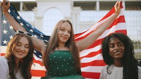 three female multiracial friends one inclusive woman in a wheelchair celebrate together while holding an American flag on a sunny day at a public park - Powered by Shutterstock - Get 15% off with code: PIKWIZARD15