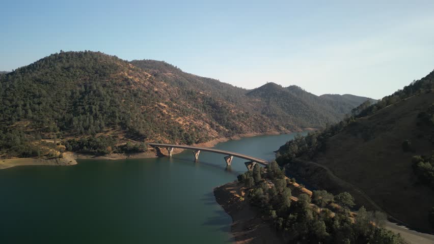 Aerial of Highway 49 bridge across Don Pedro Lake in California with mountains in backgorund