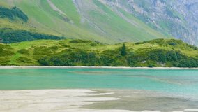 A tranquil sea-green lake lies hidden among soaring alpine peaks, with clouds drifting overhead like whispered thoughts. Switzerland, August 15, 2025 - Powered by Shutterstock - Get 15% off with code: PIKWIZARD15