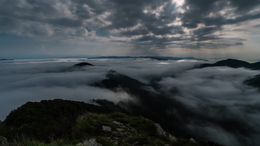 Moonlight Rays Shining Through Clouds Sky Over Misty Mountains at Full Moon Night Time Lapse