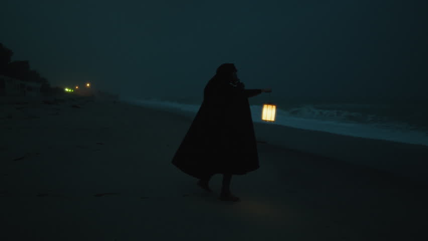 Halloween Night A Man With A Cloak And A Lantern Mysteriously Wanders The Beach