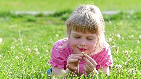 Little girl lying on the grass and playing with a spring's flower,Slow motion,high speed camera