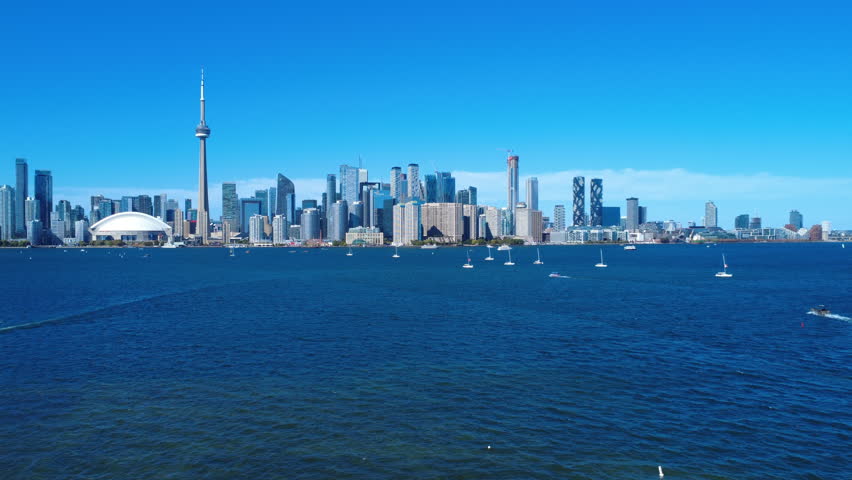 Cinematic aerial drone footage of Toronto city with a clear view of the CN Tower, captured from Toronto Island. Creating a vibrant mix of urban skyline and waterfront activity.