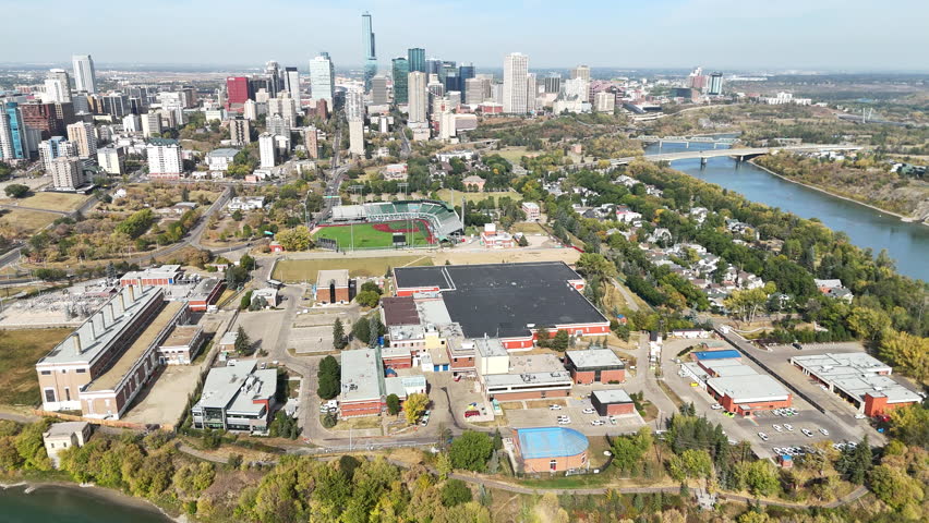 Aerial view of Edmonton city skyline and North Saskatchewan River on a sunny day, vibrant urban scene.