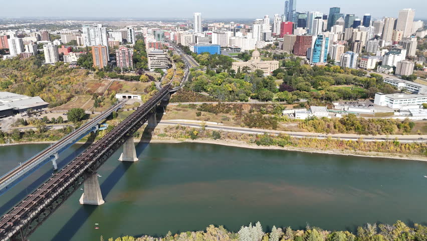 Drone video of downtown skyline with river and modern bridges, showing urban landscape and clear blue sky.