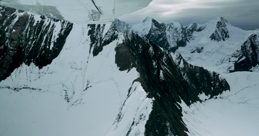 Snowy mountain peaks in Denali National Park, Alaska. POV flying small floatplane along high mountains.