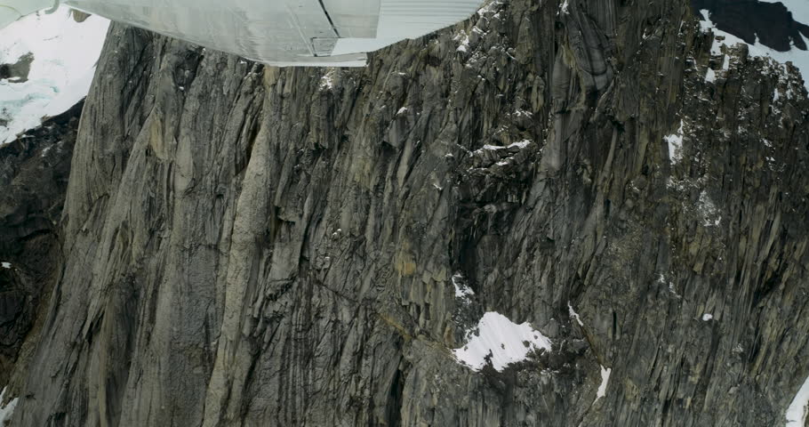 Aerial shot of snowy peaks in Alaska. Flying small plane along Denali National Park high mountains