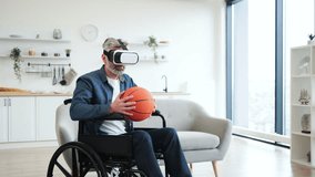 Senior man sitting in wheelchair indoors wears VR headset holding basketball, enjoying technology. Interior setting includes sofa, shelves. Emphasizes virtual reality, accessibility - Powered by Shutterstock - Get 15% off with code: PIKWIZARD15
