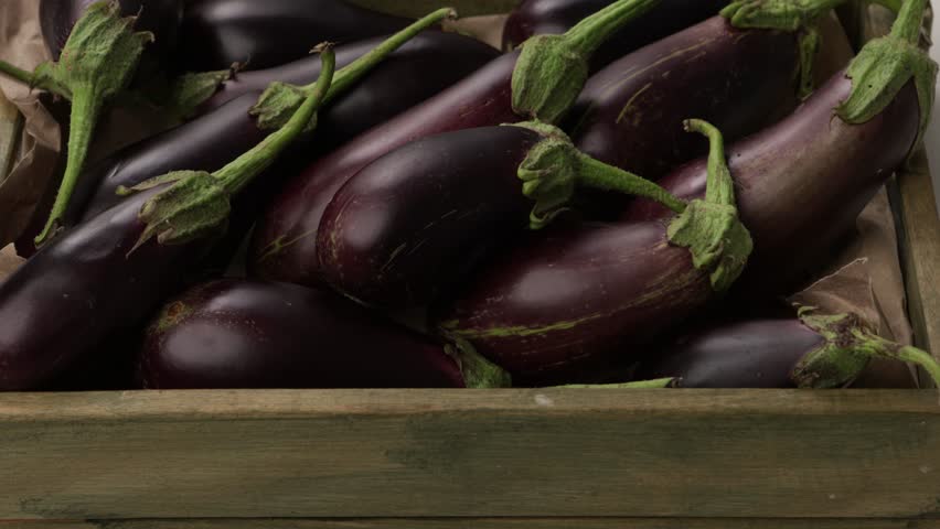 close up of uncooked eggplant in wooden crate