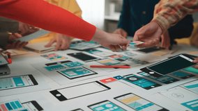 A diverse group of professionals collaborates in an office setting, developing mobile app prototypes. Innovative ideas flow as they discuss user interface design elements. SACTR - Powered by Shutterstock - Get 15% off with code: PIKWIZARD15